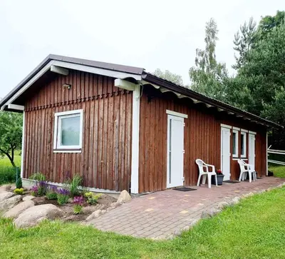 a small wooden cabin with a porch and a patio at Camp Genys in Jurbarkas