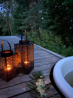 two lanterns on a deck next to a bath tub at Birštonas Tiny Hemp House in Birštonas