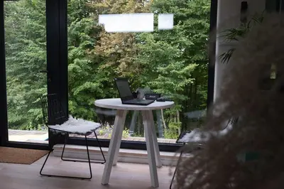 a table with a laptop on it in front of a window at Birštonas Tiny Hemp House in Birštonas