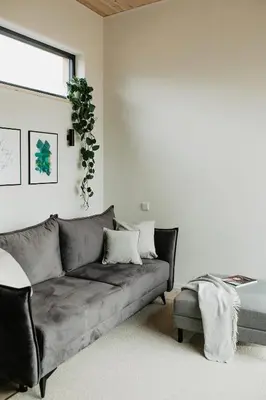 a living room with a gray couch and a window at Birštonas Tiny Hemp House in Birštonas