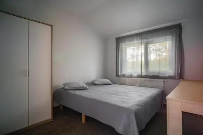 a bedroom with a bed and a window at Vėjo Malūnų sodyba - vila in Paserninkai