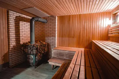 a sauna with a wood stove and a bench at Vėjo Malūnų sodyba - vila in Paserninkai