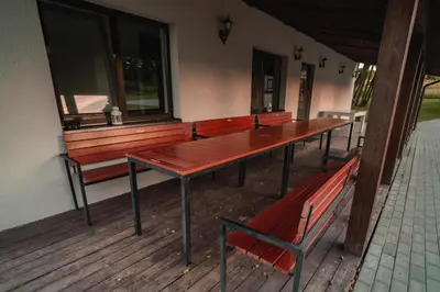 a row of tables and benches on a porch at Vėjo Malūnų sodyba - vila in Paserninkai