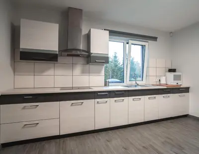 a kitchen with white cabinets and a sink and a window at Vėjo Malūnų sodyba - vila in Paserninkai