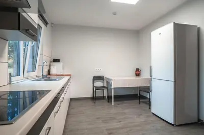 a kitchen with a white refrigerator and a table at Vėjo Malūnų sodyba - vila in Paserninkai
