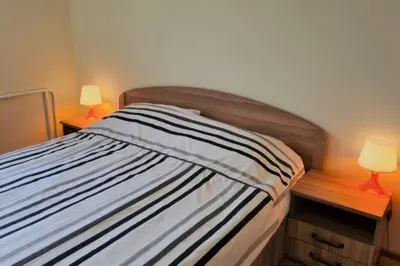 a bedroom with a bed with two lamps on tables at Butas Ignalinos centre poilsiui ir darbostogoms in Ignalina