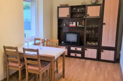 a dining room with a table and a tv at Butas Ignalinos centre poilsiui ir darbostogoms in Ignalina
