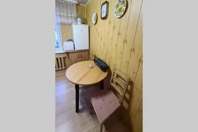 a kitchen with a wooden table and a chair at Butas Ignalinos centre poilsiui ir darbostogoms in Ignalina