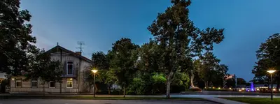 an old building with trees in front of it at night at à la fontaine in Druskininkai