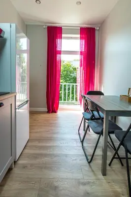 a kitchen with a table and a window with red curtains at à la fontaine in Druskininkai