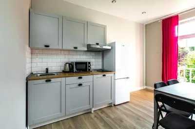 a kitchen with white cabinets and a table in a room at à la fontaine in Druskininkai