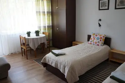 a bedroom with a bed and a table with a chair at Mildos butas in Birštonas