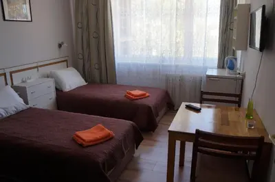 a hotel room with two beds and a table and a window at Mildos butas in Birštonas