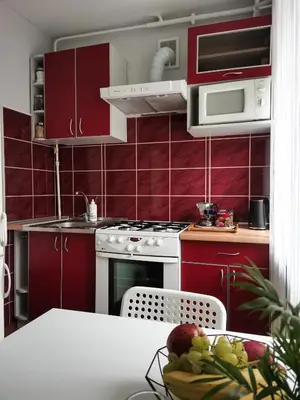 a kitchen with red cabinets and a table with a bowl of fruit at The good stay in Šiauliai