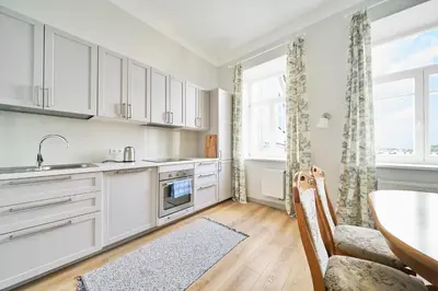 a kitchen with white cabinets and a table and a chair at Lovely, Best View Apartment, Vilnius City Centre in Vilnius