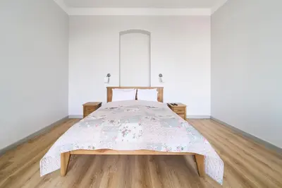 a bed in a white room with a wooden floor at Lovely, Best View Apartment, Vilnius City Centre in Vilnius