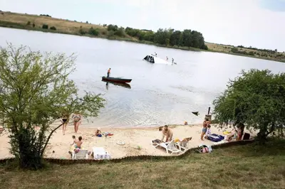 a group of people on a beach with a boat in the water at 3 Apartment Between two lakes in Vilnius