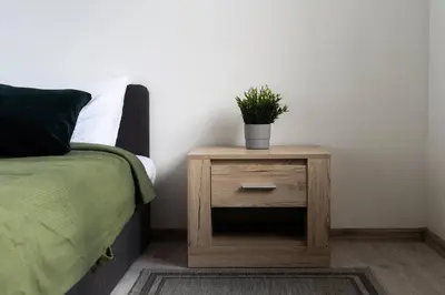a nightstand with a plant on it next to a bed at 2 House Between two lakes in Vilnius