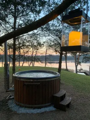 a hot tub in a tree with two benches at Kedras Glamping - Pod tipo nameliai in Prapuntai