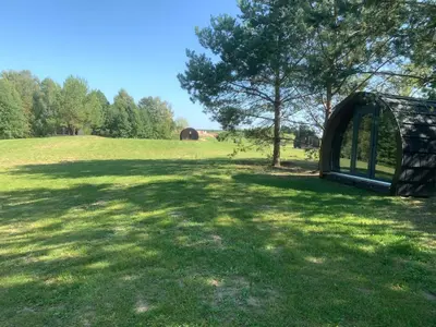 a large field with a tree and an archway at Kedras Glamping - Pod tipo nameliai in Prapuntai