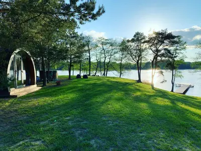 a grassy area with a dock and a body of water at Kedras Glamping - Pod tipo nameliai in Prapuntai