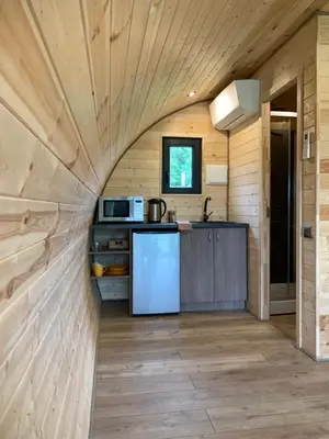 a kitchen in a tiny house with wooden walls at Kedras Glamping - Pod tipo nameliai in Prapuntai