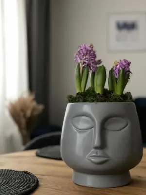 a planter with a face with purple flowers in it at Forest Studio in Druskininkai