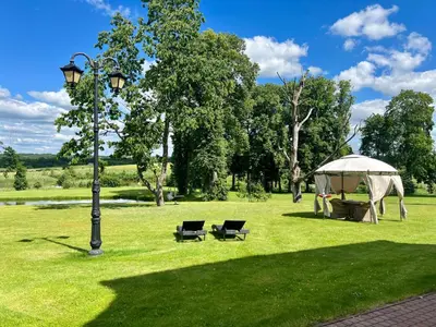 a tent and two chairs in a park with a light pole at Pakėvio dvaras - Pakevis manor in Kelmė
