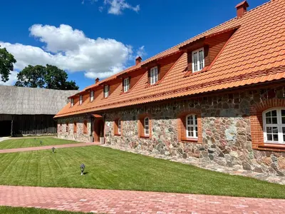 a large brick building with a red roof at Pakėvio dvaras - Pakevis manor in Kelmė