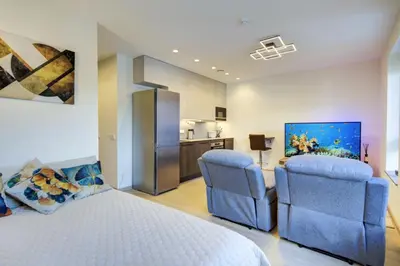 a bedroom with a bed and two chairs and a kitchen at Kaunas City Center Deluxe in Kaunas