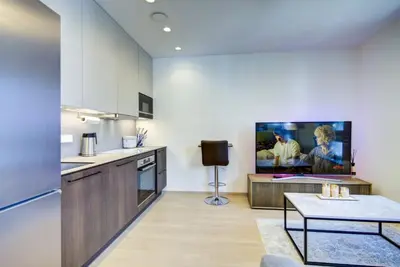 a kitchen with a table and a tv on the wall at Kaunas City Center Deluxe in Kaunas
