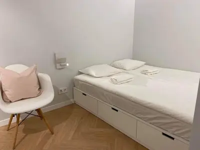 a small bedroom with a bed and a chair at Vytautas Park Apartment with FREE Parking in Marijampolė
