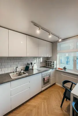 a kitchen with white cabinets and a wooden floor at Vytautas Park Apartment with FREE Parking in Marijampolė