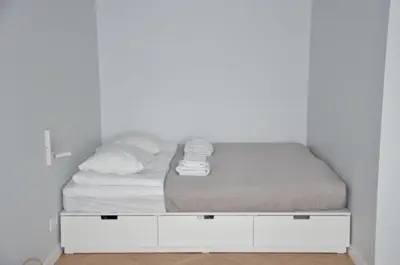a bed in a room with a white wall at Vytautas Park Apartment with FREE Parking in Marijampolė
