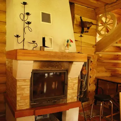 a fireplace with a television in a log cabin at Likimo ratas in Paliepis