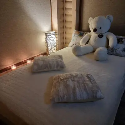 a white teddy bear sitting on a bed with lights at Žuvininkų pirtelė in Šiauliai