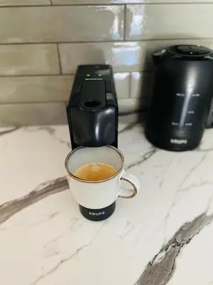 a cup of coffee on a counter next to a toaster at Greenwood apartments in Druskininkai