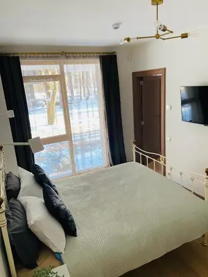 a bedroom with a bed and a large window at Greenwood apartments in Druskininkai