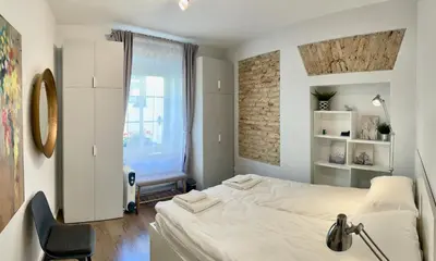 a bedroom with a white bed and a chair at Uzupis Deluxe Retreat in Old Town Vilnius in Vilnius