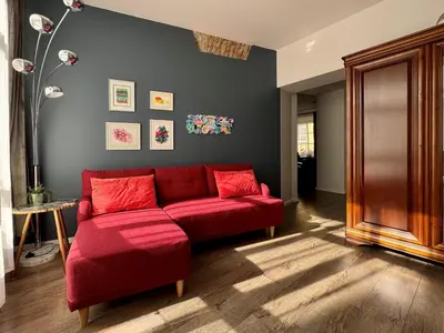 a living room with a red couch in a room at Uzupis Deluxe Retreat in Old Town Vilnius in Vilnius