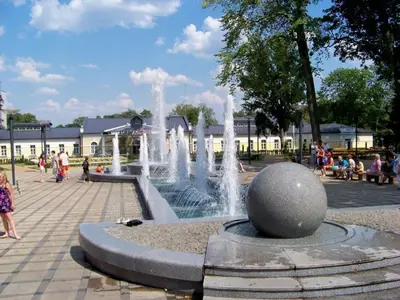 a fountain in a park with people walking around it at Apartment in Druskininkai City Centre in Druskininkai