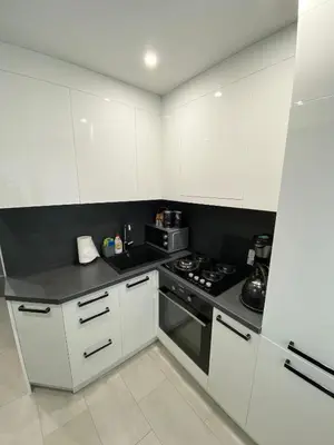 a kitchen with white cabinets and a stove top oven at Studio flat in Panevezys in Panevėžys