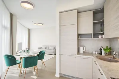 a kitchen with white cabinets and a table and chairs at Apartment DoMiSol in Druskininkai