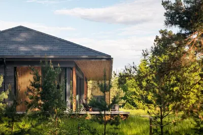 a small house in a field with trees at The Lake - Waterfront Villas Retreat in Mindūnai