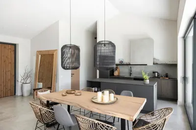 a kitchen and dining room with a wooden table and chairs at The Lake - Waterfront Villas Retreat in Mindūnai