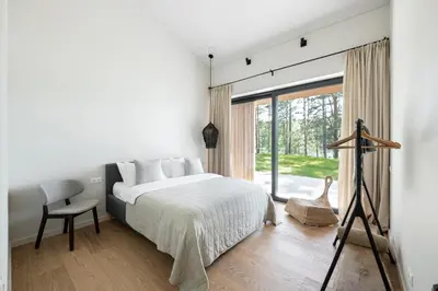 a bedroom with a bed and a large window at The Lake - Waterfront Villas Retreat in Mindūnai