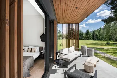 a screened in porch with a couch and a table at The Lake - Waterfront Villas Retreat in Mindūnai