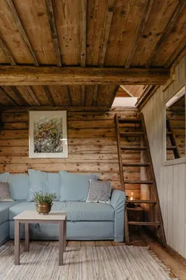 a living room with a blue couch and a table at Vienkiemio Oazė - Namelis Prie Upelio in Galvokai