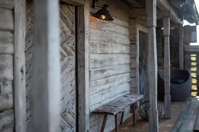 a wooden cabin with a bench and a lamp at Vienkiemio Oazė - Namelis Prie Upelio in Galvokai