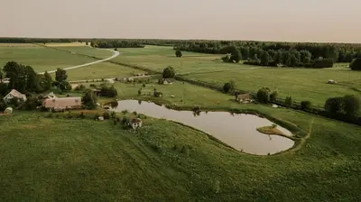 an aerial view of a farm with a pond at Vienkiemio Oazė - Namelis Prie Upelio in Galvokai
